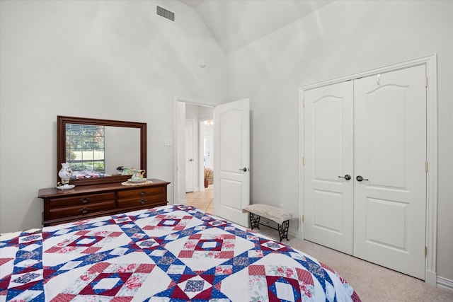 bedroom featuring a closet, high vaulted ceiling, and light colored carpet