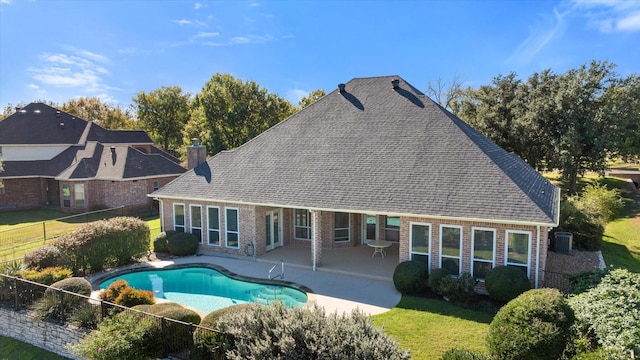 rear view of property with a patio, a fenced in pool, and a lawn