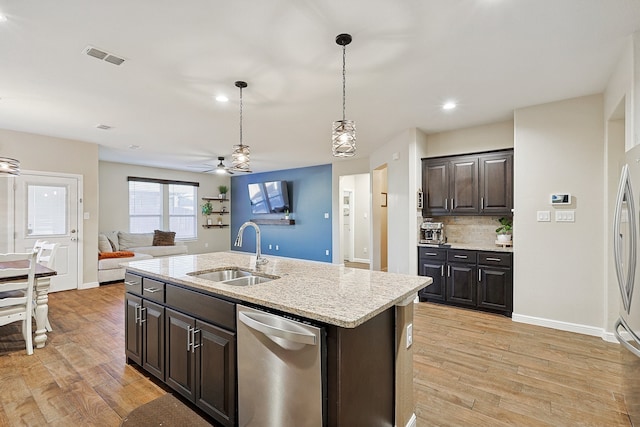 kitchen featuring dark brown cabinets, sink, pendant lighting, light hardwood / wood-style flooring, and an island with sink