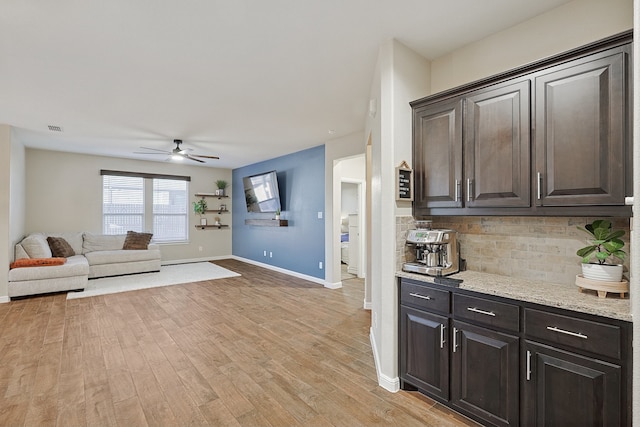 kitchen featuring light stone countertops, light wood-type flooring, tasteful backsplash, dark brown cabinets, and ceiling fan