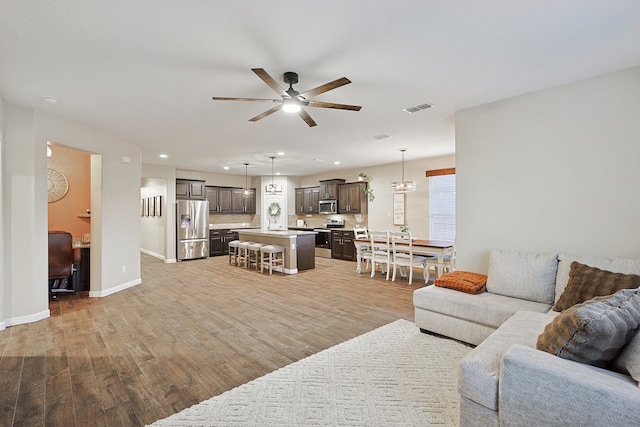 living room with light hardwood / wood-style floors and ceiling fan