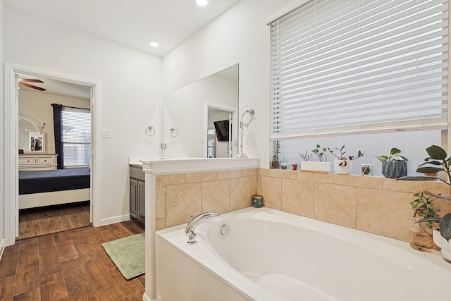 bathroom with a bathing tub, ceiling fan, vanity, and wood-type flooring