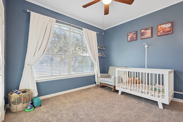 bedroom with a crib, carpet flooring, ceiling fan, and crown molding