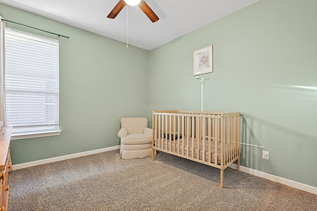 bedroom featuring multiple windows, ceiling fan, carpet, and a crib