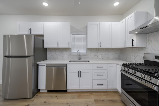 kitchen featuring sink, white cabinets, wall chimney range hood, and appliances with stainless steel finishes