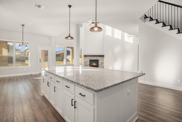 kitchen featuring hanging light fixtures, white cabinetry, plenty of natural light, and a stone fireplace