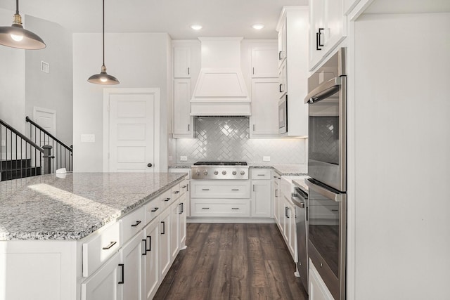 kitchen featuring custom exhaust hood, tasteful backsplash, white cabinetry, appliances with stainless steel finishes, and pendant lighting