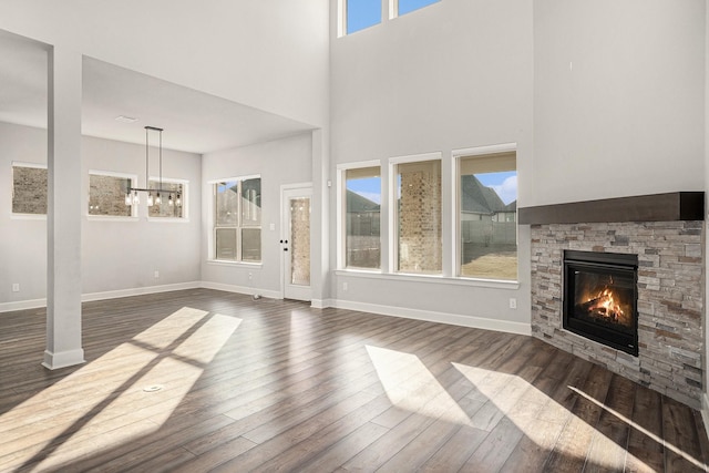 unfurnished living room with a fireplace, plenty of natural light, dark hardwood / wood-style floors, and a towering ceiling