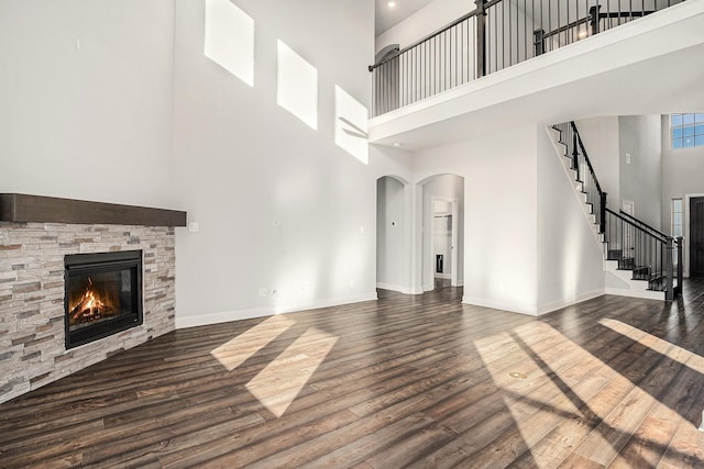 unfurnished living room with dark wood-type flooring, a fireplace, and a high ceiling