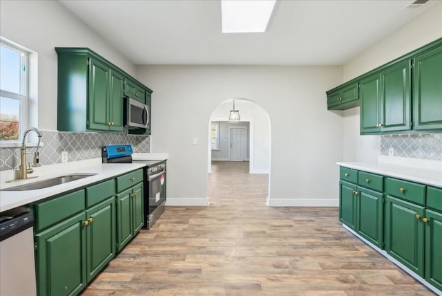 kitchen with sink, green cabinetry, light hardwood / wood-style flooring, stainless steel appliances, and backsplash