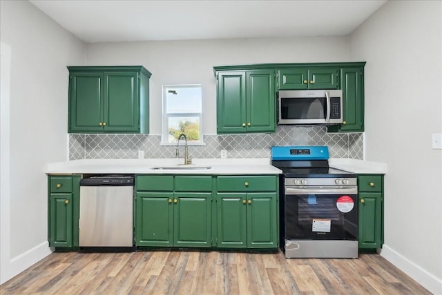 kitchen featuring sink, green cabinetry, light hardwood / wood-style flooring, stainless steel appliances, and decorative backsplash