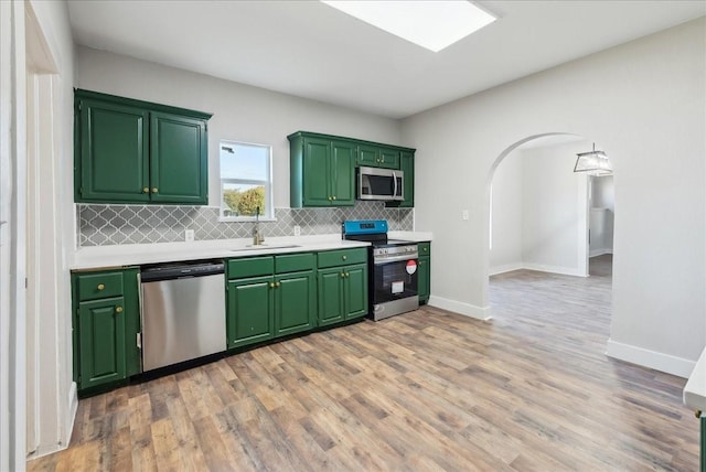 kitchen featuring stainless steel appliances, tasteful backsplash, sink, and light hardwood / wood-style floors