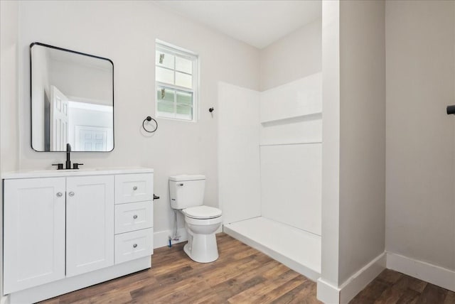 bathroom featuring vanity, hardwood / wood-style floors, walk in shower, and toilet