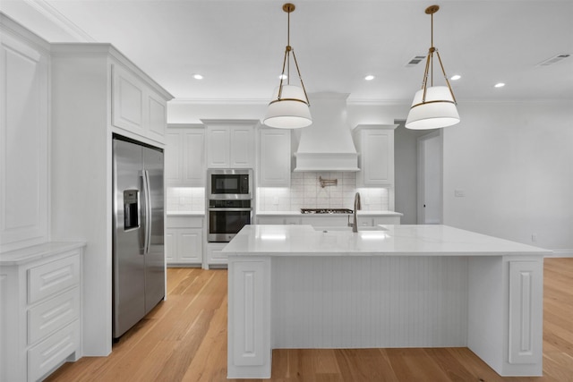 kitchen featuring appliances with stainless steel finishes, premium range hood, light hardwood / wood-style flooring, and decorative light fixtures