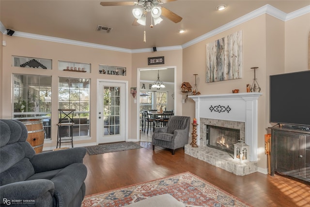 living room with crown molding, hardwood / wood-style floors, ceiling fan, and a brick fireplace