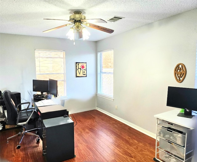 office with plenty of natural light, dark wood-type flooring, and a textured ceiling