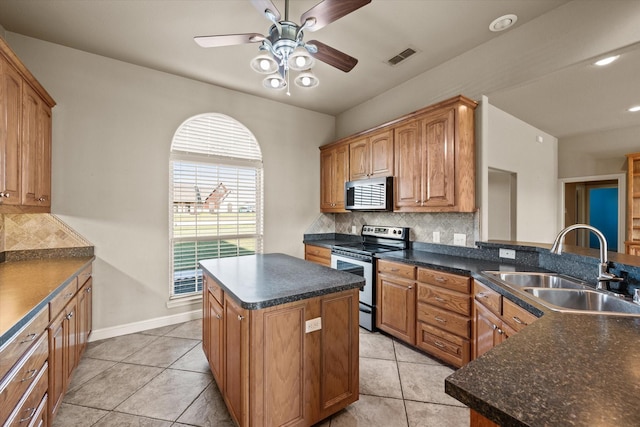 kitchen with ceiling fan, a center island, sink, stainless steel appliances, and tasteful backsplash