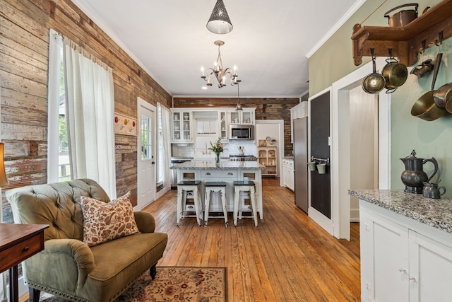 kitchen with white cabinets, decorative light fixtures, stainless steel appliances, and wooden walls