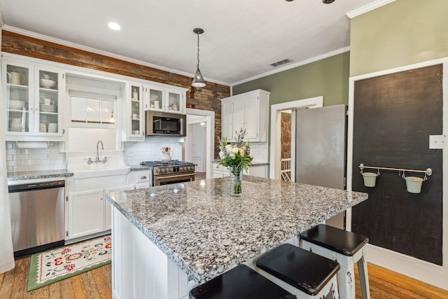 kitchen featuring sink, a breakfast bar area, light wood-type flooring, white cabinetry, and stainless steel appliances