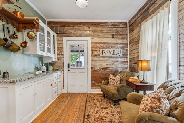 living room featuring crown molding, light hardwood / wood-style flooring, and wood walls