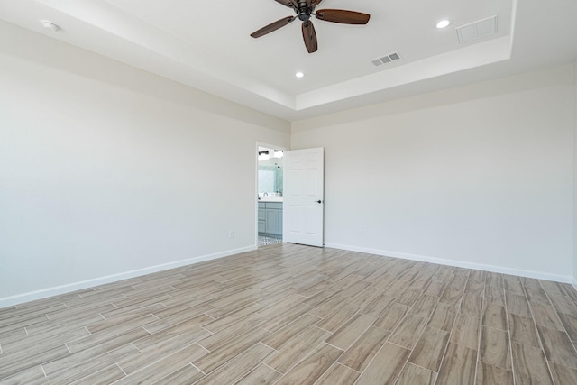 empty room featuring a tray ceiling and ceiling fan