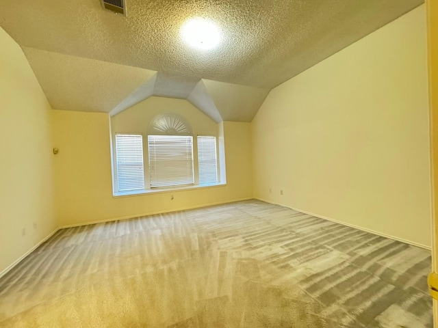 bonus room with a textured ceiling, light carpet, and vaulted ceiling