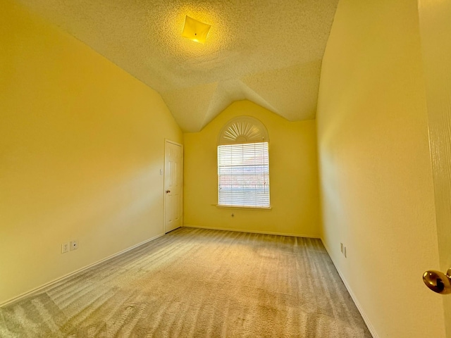 carpeted spare room with a textured ceiling and lofted ceiling