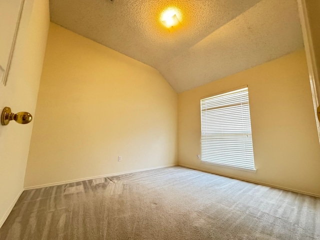 spare room with vaulted ceiling, carpet flooring, and a textured ceiling