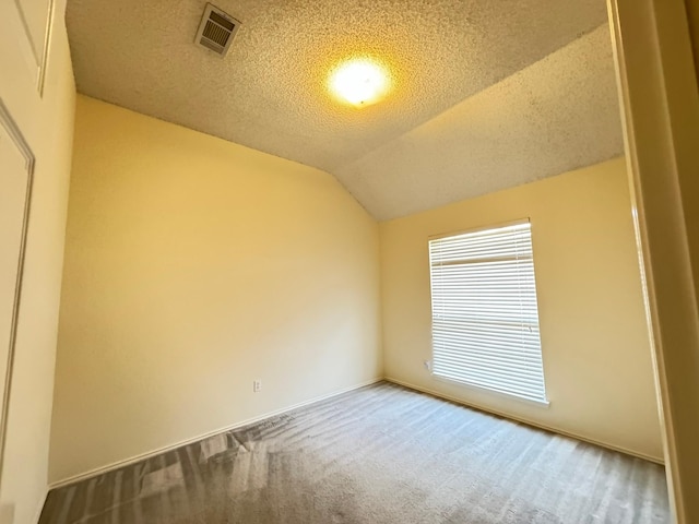 empty room with vaulted ceiling, carpet floors, and a textured ceiling