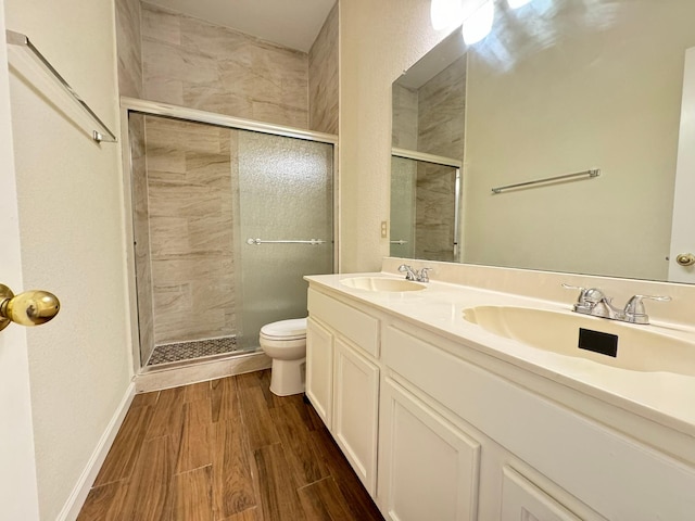 bathroom with hardwood / wood-style floors, vanity, toilet, and a shower with door