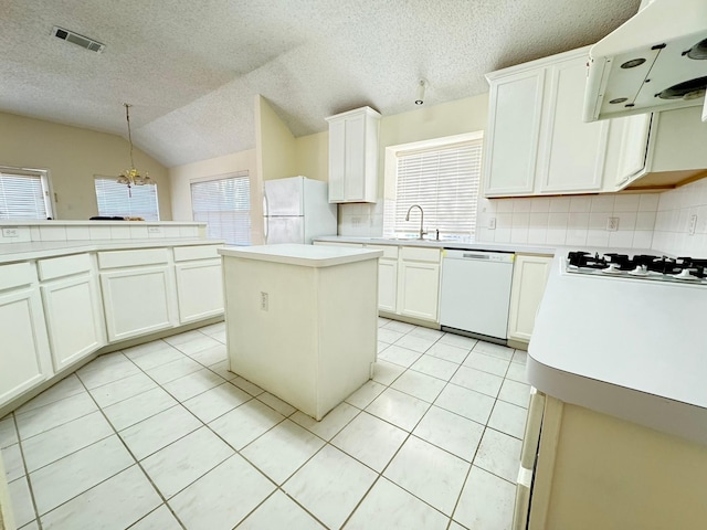 kitchen with decorative backsplash, white appliances, decorative light fixtures, a center island, and lofted ceiling