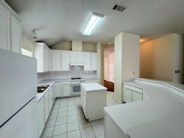 kitchen featuring backsplash, white appliances, light tile patterned floors, white cabinets, and a kitchen island