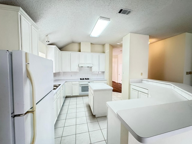 kitchen featuring white cabinetry, kitchen peninsula, a kitchen island, white appliances, and decorative backsplash