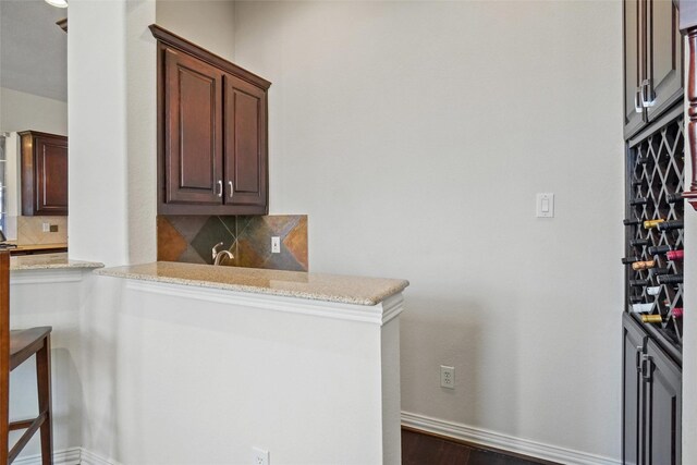 interior space with dark hardwood / wood-style flooring, light stone counters, dark brown cabinetry, and tasteful backsplash