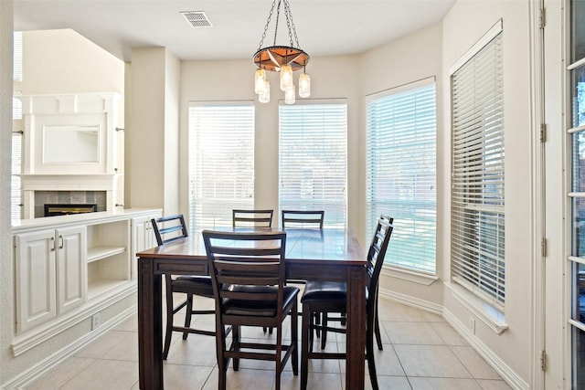 dining area featuring light tile patterned floors, an inviting chandelier, and a tiled fireplace