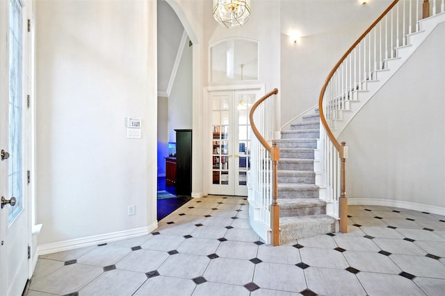 foyer entrance with a chandelier, high vaulted ceiling, and french doors