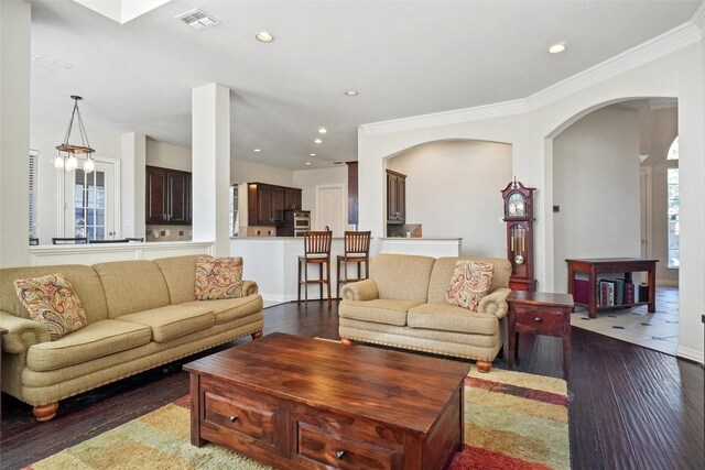 living room with dark hardwood / wood-style flooring, ornamental molding, and a chandelier