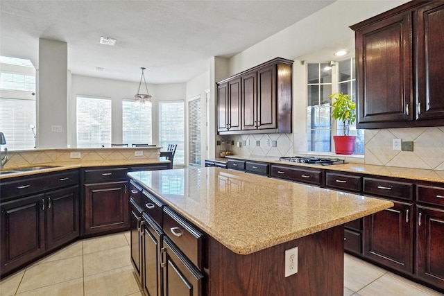 kitchen with backsplash, a center island, hanging light fixtures, and stainless steel gas stovetop