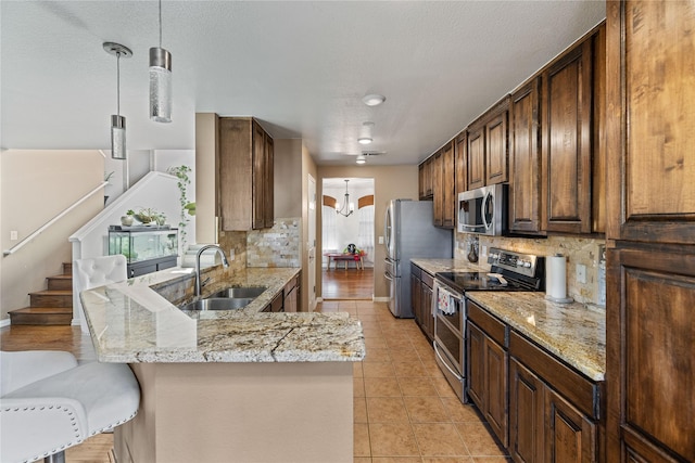 kitchen with sink, backsplash, kitchen peninsula, a breakfast bar, and appliances with stainless steel finishes