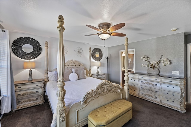 bedroom with a textured ceiling, ceiling fan, dark carpet, and ensuite bathroom