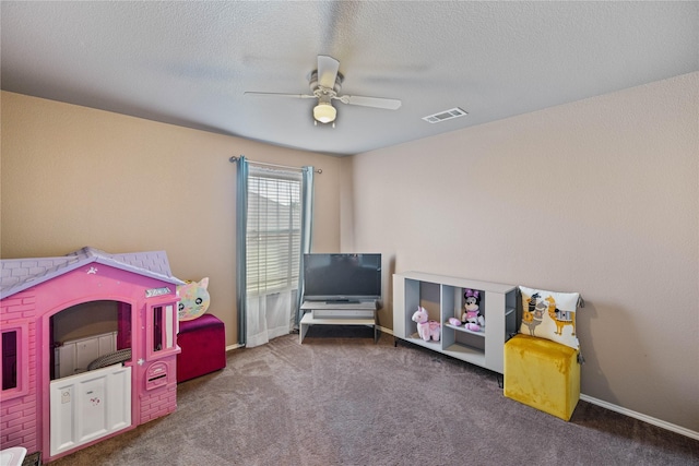 rec room featuring ceiling fan, dark carpet, and a textured ceiling