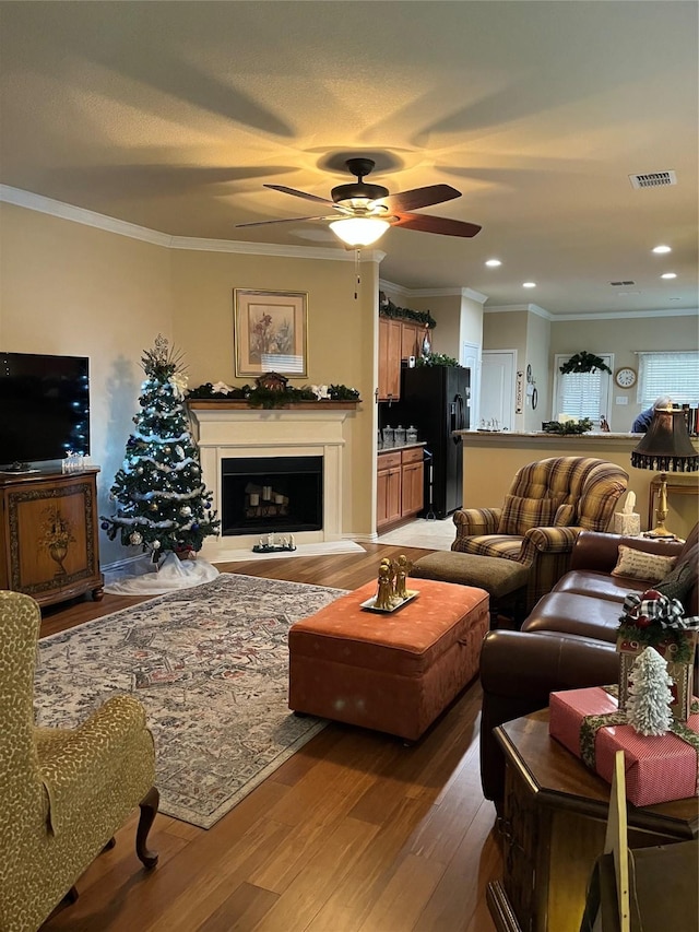 living room featuring crown molding, light hardwood / wood-style flooring, and ceiling fan