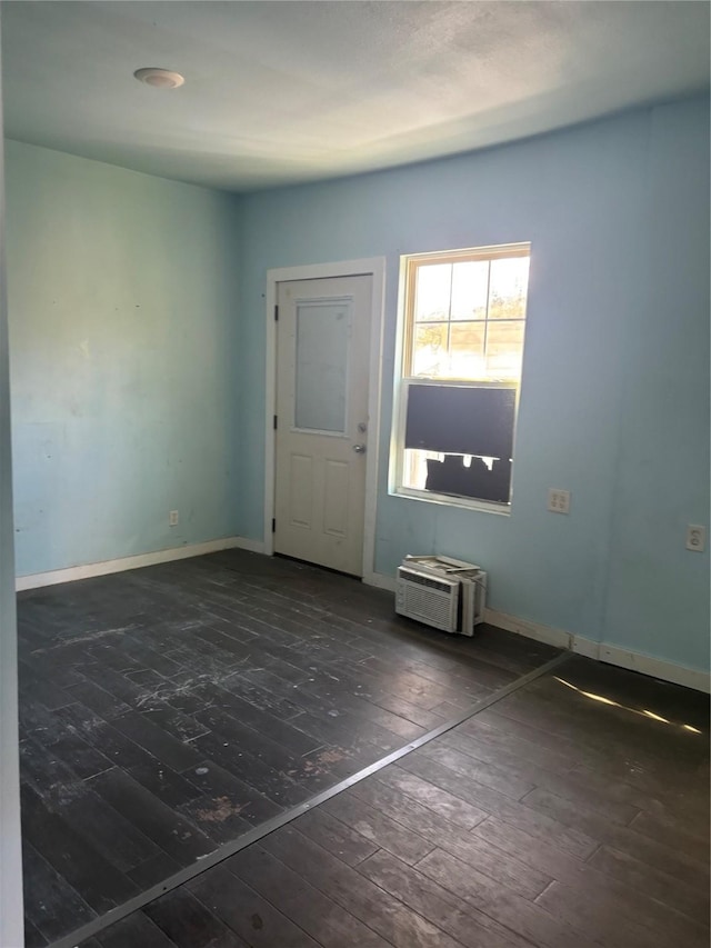 empty room featuring a wall mounted AC and dark wood-type flooring