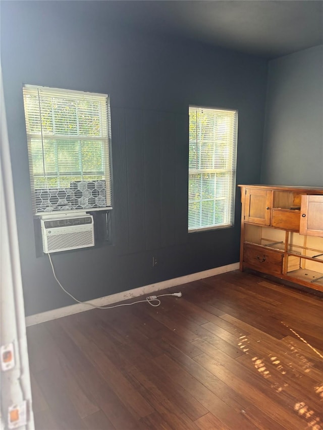 unfurnished bedroom featuring multiple windows, cooling unit, and dark wood-type flooring