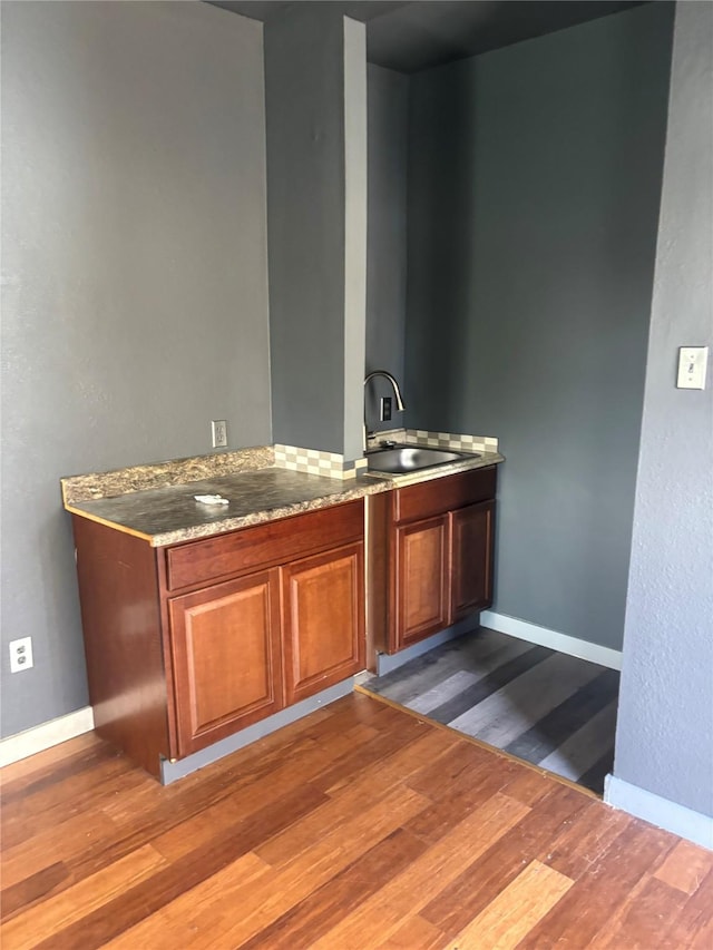 bar featuring dark hardwood / wood-style floors, light stone countertops, and sink