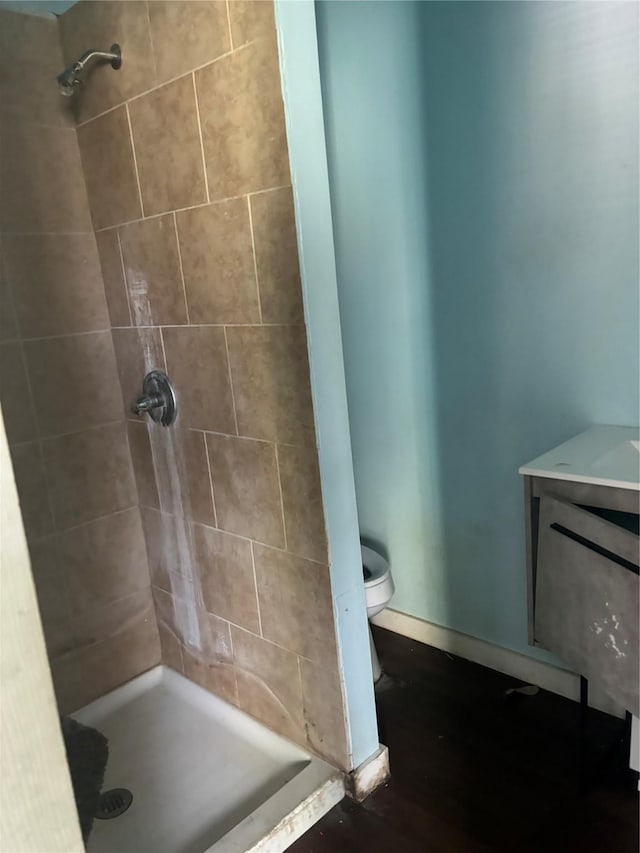 bathroom featuring toilet, wood-type flooring, and tiled shower