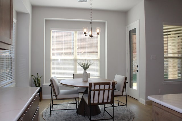 dining space featuring a healthy amount of sunlight, light wood-type flooring, and a chandelier