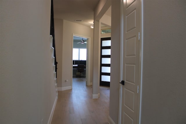 hallway featuring decorative columns and light hardwood / wood-style flooring