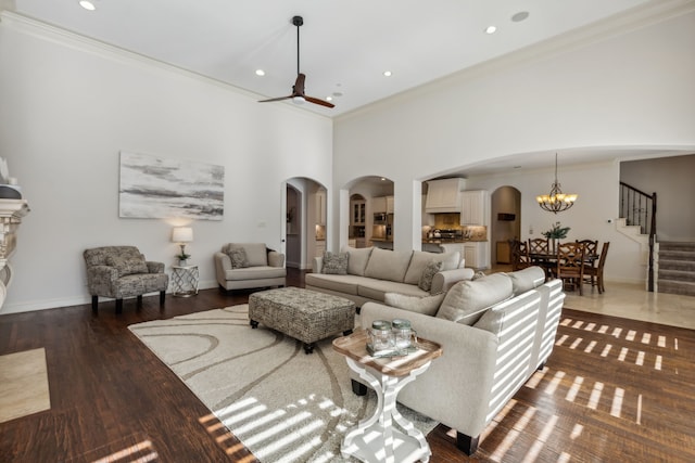 living room with crown molding, dark hardwood / wood-style flooring, a high ceiling, and ceiling fan with notable chandelier