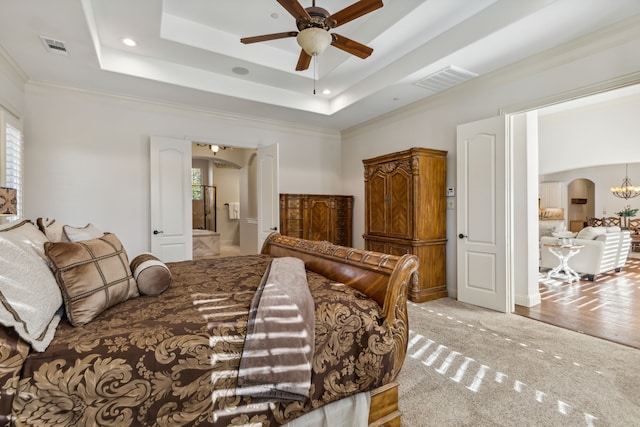 bedroom featuring ceiling fan with notable chandelier, multiple windows, light carpet, and ensuite bath